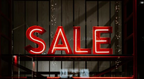 A red neon Sale sign is seen in a store window