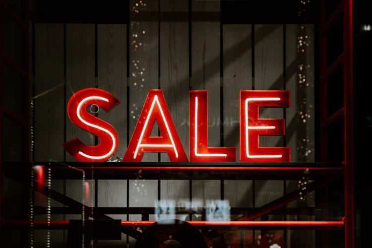 A red neon Sale sign is seen in a store window