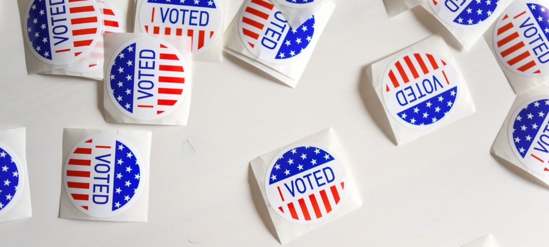 A scattering of small round stickers reading "I voted" lay on a white table