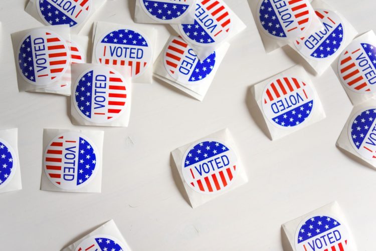 A scattering of small round stickers reading "I voted" lay on a white table