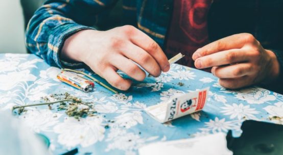 Man rolling a joint with zig zag papers