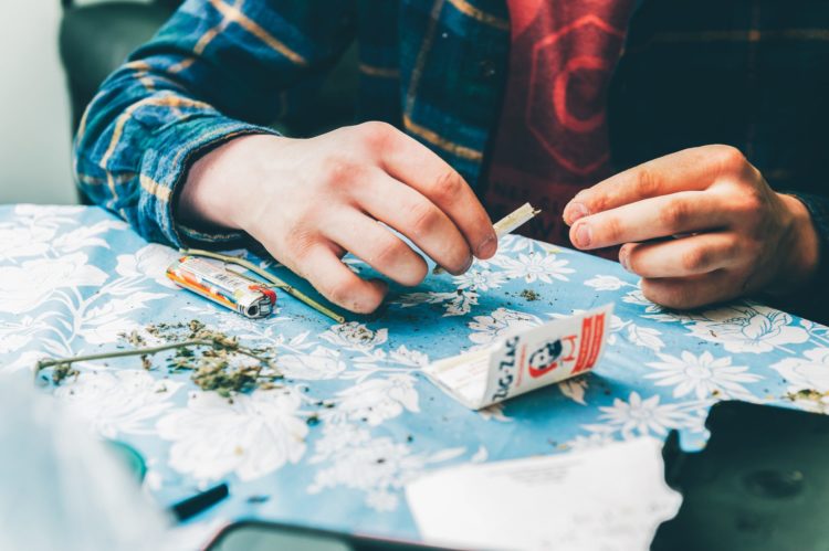 Man rolling a joint with zig zag papers