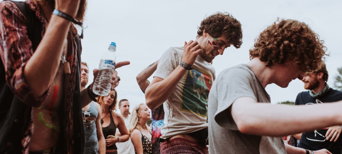 A group of festival goers dance and smoke cannabis