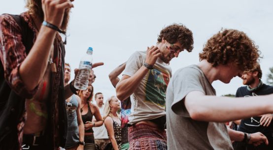 A group of festival goers dance and smoke cannabis