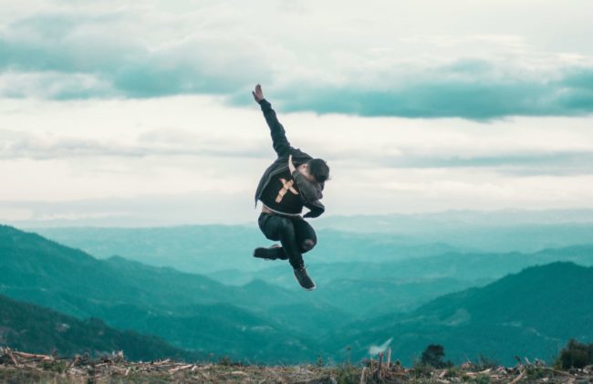 A man jumps and does "the Dab" high above a city